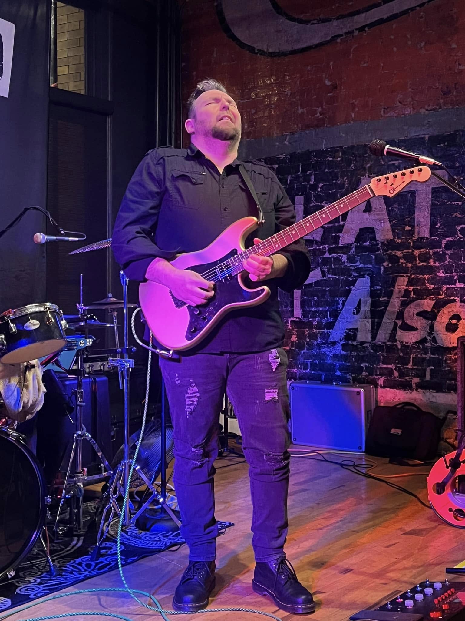 Billy Parvin playing guitar under purple lights